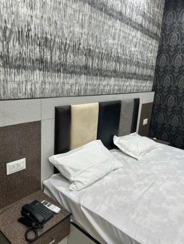 a bedroom with a bed with a phone on a table at Nawabz Hotel in Karnal