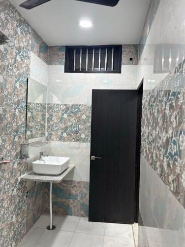 a bathroom with a sink and a black door at Nawabz Hotel in Karnal