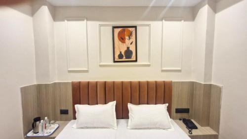 a bedroom with a bed with a wooden headboard at The City Hotel in Kānpur