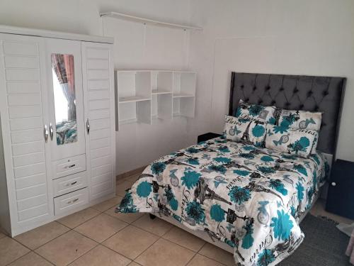 a bedroom with a bed and a dresser and a closet at Charles Guest House in Germiston