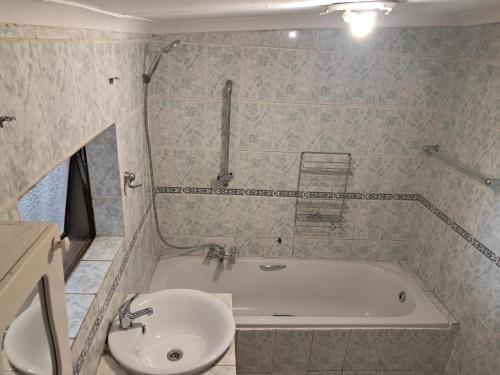 a bathroom with a tub and a sink at Charles Guest House in Germiston