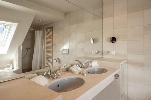 a bathroom with two sinks and a large mirror at Carlton-Europe Vintage Adults Hotel in Interlaken