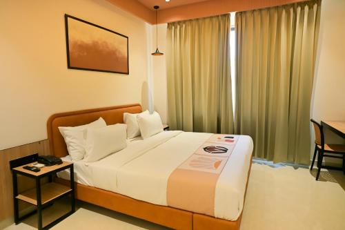 a bedroom with a bed and a window with a desk at Hotel Walnut - Near Jaipur Airport in Jaipur
