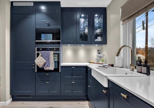 a kitchen with navy blue cabinets and a sink at Sunny Garden Stay in Sandvika