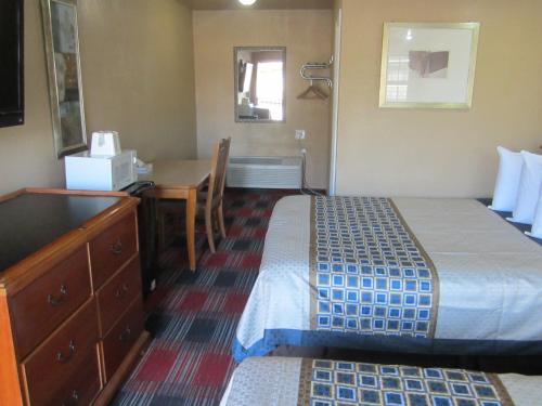 a small hotel room with a bed and a desk at Little Boy Blue Motel in Anaheim