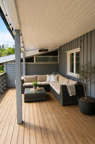 a patio with a couch and tables on a deck at Sunny Garden Stay in Sandvika
