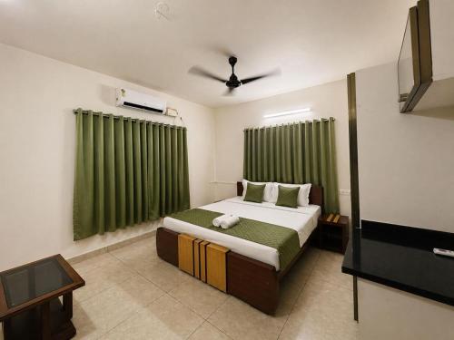 a bedroom with a large bed with green curtains at Blanco Airport Suite in Kāladi