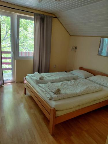 a large bed in a room with two windows at Joky Katona Rooms & Apartments in Palić