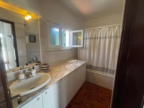 a white bathroom with a sink and a mirror at Casa do Meco - Private Pool in Sesimbra