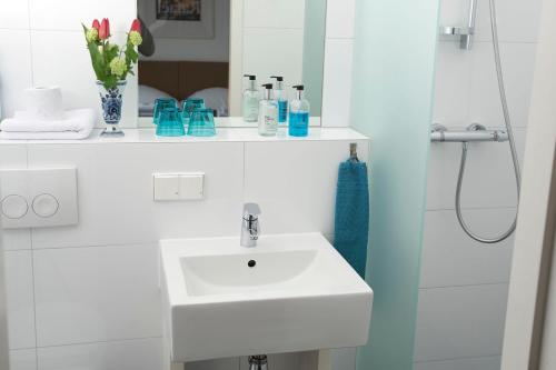 a white bathroom with a sink and a shower at Bed & Breakfast Hotel Malts in Haarlem