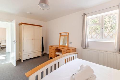 a bedroom with a bed and a desk and a mirror at Spacious Riverside View Bungalow in Oxford