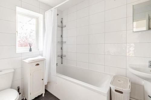 a white bathroom with a tub and a toilet and a sink at Spacious Riverside View Bungalow in Oxford