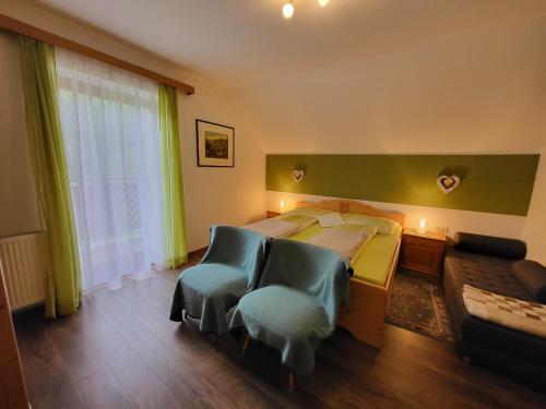 a bedroom with a bed and two blue chairs at Ferienhaus Gstoderblick in Seebach