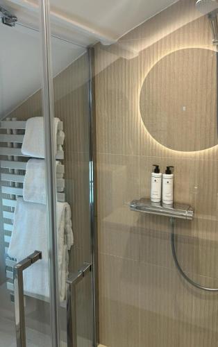 a bathroom with a shower with a mirror and towels at Hotel Restaurant Les Venetes in Arradon