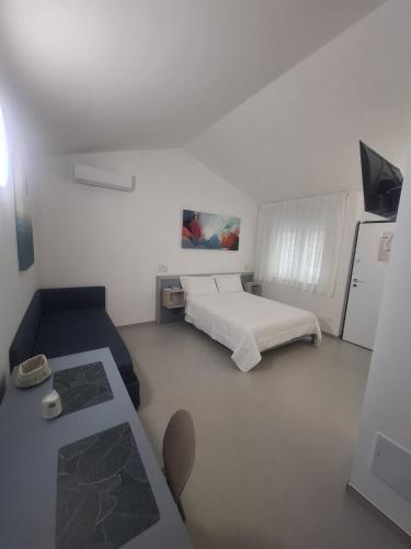 a white bedroom with a bed and a couch at Le Casette Del Mare in Crotone