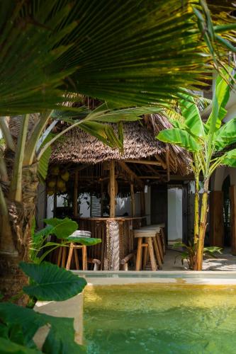 a resort building with a table and chairs and palm trees at Mlango Paje Villa Boutique in Paje