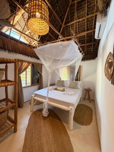 a bedroom with a bed with a mosquito net at Mlango Paje Villa Boutique in Paje