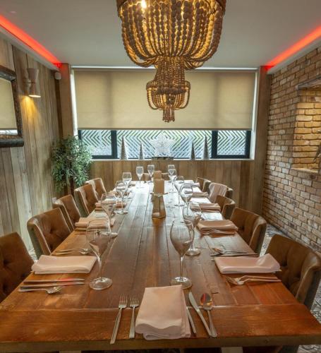 a long wooden table with chairs and a chandelier at Claremont Hotel in Alloa