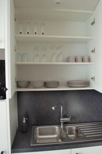 a kitchen sink with plates and glasses on shelves at Zilte bries in Nieuwpoort