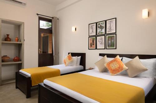 two beds in a room with yellow and white at Divulgaha Gedara Boutique Hotel in Anuradhapura
