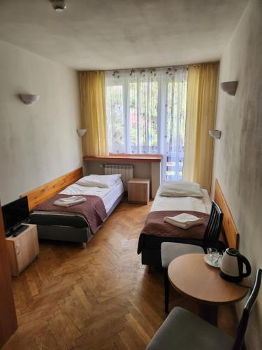 a hotel room with two beds and a table and a tv at Ośrodek Wypoczynkowy Niagara in Międzybrodzie Żywieckie