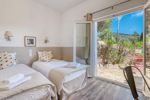 ein Schlafzimmer mit zwei Betten und einer Glasschiebetür in der Unterkunft Hôtel Paradis in Bormes-les-Mimosas