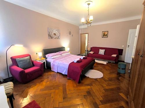 a bedroom with a bed and two red chairs at Guest House Barocco in Rovinj