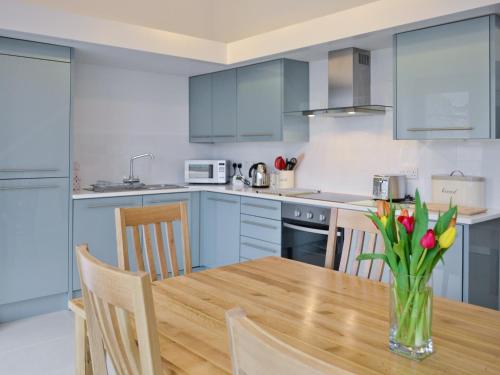 a kitchen with a wooden table with a vase of flowers at The Hayloft - Nab in Aynho