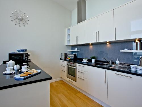 a kitchen with white cabinets and a black counter top at Bliss - Horizon View in Westward Ho