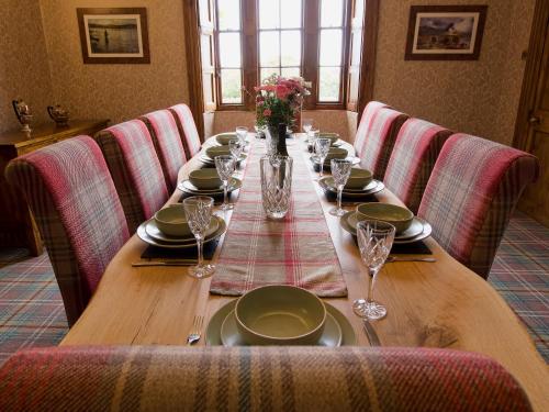 a long wooden table with plates and wine glasses at Drummuie House in Golspie