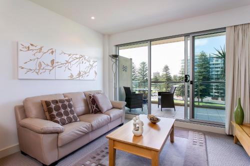 a living room with a couch and a table at Glenelg Holiday Apartments-Pier Direct Beach Front Free Parking in Adelaide