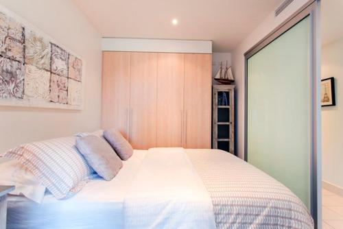 a bedroom with a white bed with pillows on it at Glenelg Holiday Apartments-Pier Direct Beach Front Free Parking in Adelaide