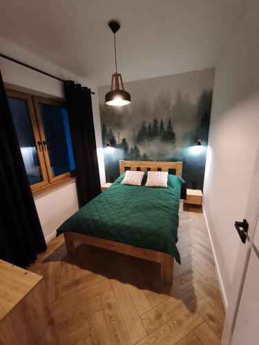 a bedroom with a green bed with a painting on the wall at Kropla Rosy 27 in Orchówek