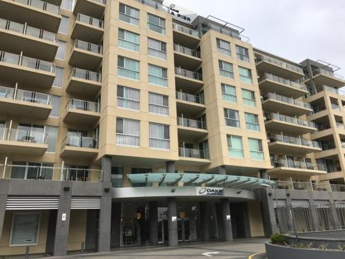 a large apartment building in front of a parking lot at Glenelg Holiday Apartments-Pier Direct Beach Front Free Parking in Adelaide