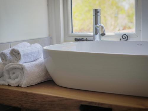 a white bath tub sitting on a table in a bathroom at Mallard Cottage in Winchester