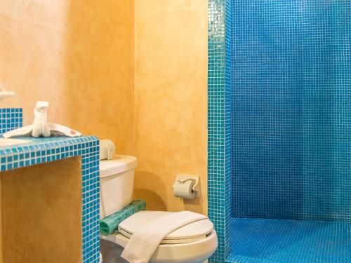 a bathroom with a toilet and a blue glass shower at Hotel Barrio Latino in Playa del Carmen