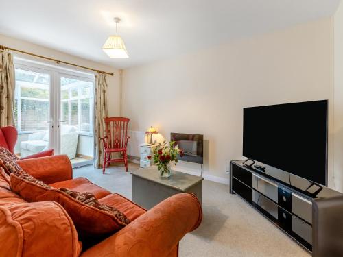 a living room with a couch and a flat screen tv at Pine Cottage - Uk46874 in Hartland