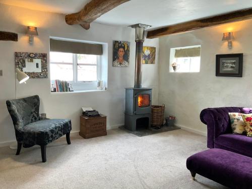 a living room with a wood stove and a chair at Granny Mcphees Cottage Hssh in Beaworthy