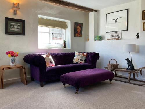 a living room with a purple couch and a window at Granny Mcphees Cottage Hssh in Beaworthy