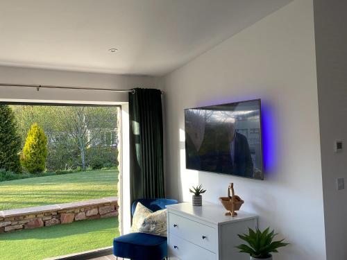 a living room with a tv and a chair and a window at Blue Heron Lodge in Brough