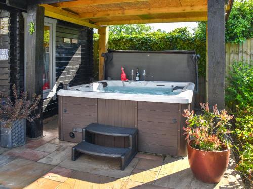 a jacuzzi tub with a bench in a yard at Myrtle Cottage in Potter Heigham