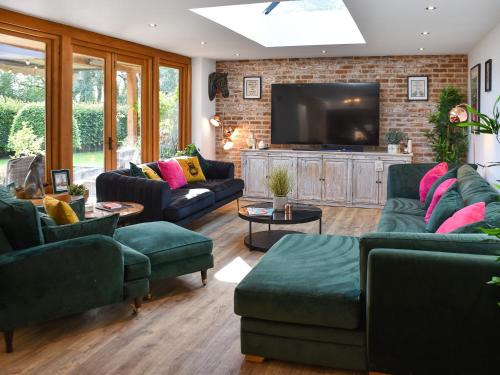 a living room with couches and a flat screen tv at Myrtle Cottage in Potter Heigham