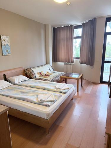 a bedroom with a large bed and a table at Persey Flora Apartments in Borovets