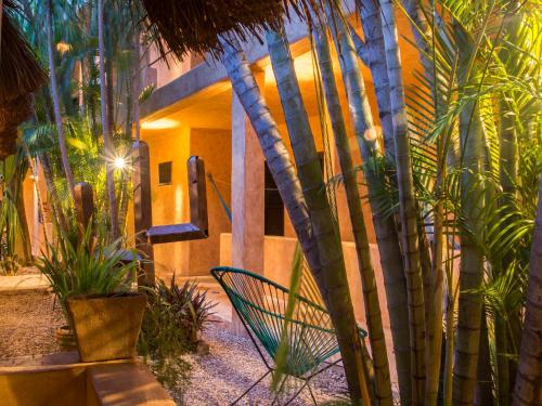 a house with palm trees and a chair in front of it at Hotel Barrio Latino in Playa del Carmen