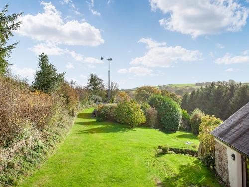 a garden with grass and trees and a house at Uk45541-Old Stable Cottage in Sticklepath