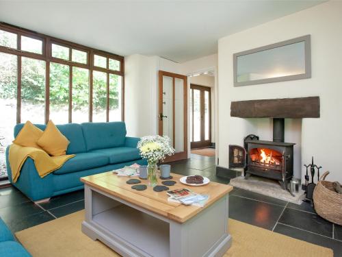 a living room with a blue couch and a fireplace at Uk45541-Old Stable Cottage in Sticklepath