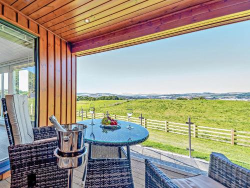 a table and chairs on a porch with a view of a field at Glencoe Luxury Lodge in Erskine