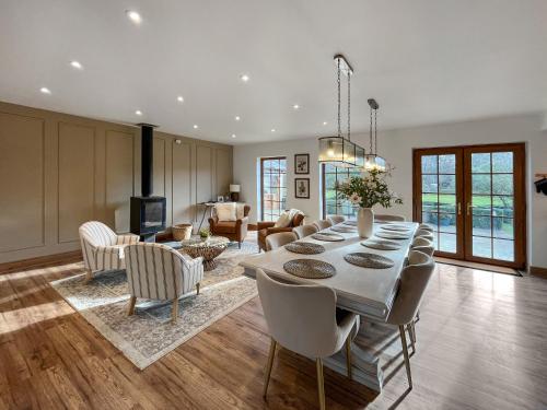 a dining room and living room with a table and chairs at Pant Ifan Goch in St Asaph