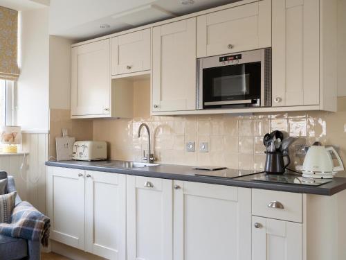 a kitchen with white cabinets and a microwave at Croft House - Uk7555 in Inverness