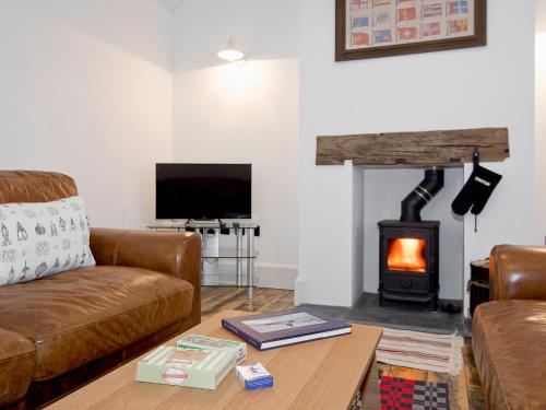 a living room with a couch and a wood stove at Ty Cai in Llanwnda
